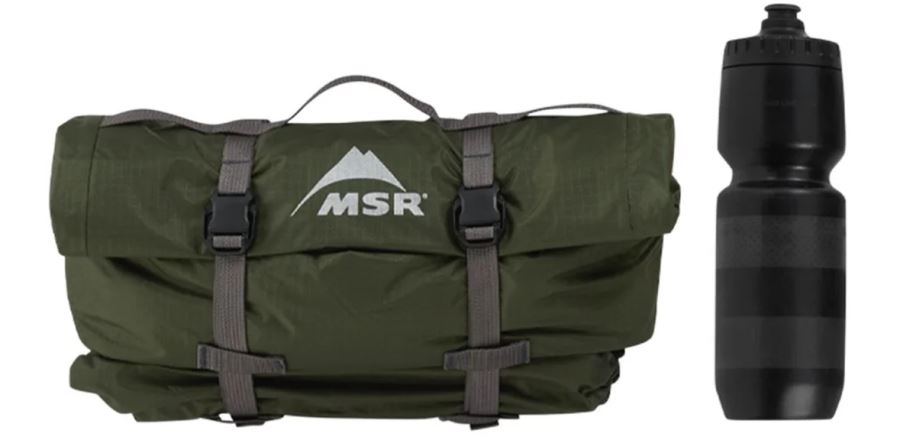Sbalený zelený stan MSR Hubba Hubba Bikepack 2 s popruhy a černou lahví. (13)