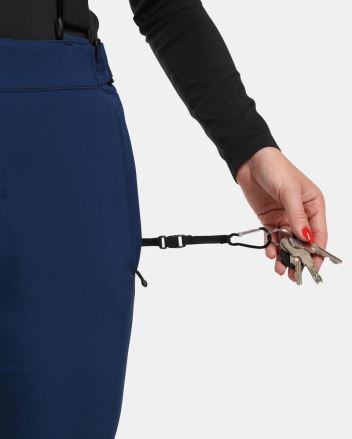 Žena vyndává klíče z praktického poutka na Dámských lyžařských kalhotách Kilpi RHEA-W tmavě modrá. (5)