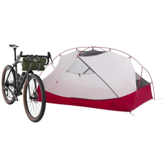 Stan MSR Hubba Hubba Bikepack 2 zelená postavený vedle bikepacking kola s taškou na řídítkách.