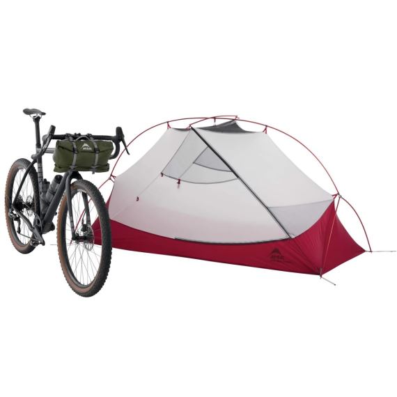 Stan MSR Hubba Hubba Bikepack 1 zelená postavený vedle kola s brašnou na řídítkách.